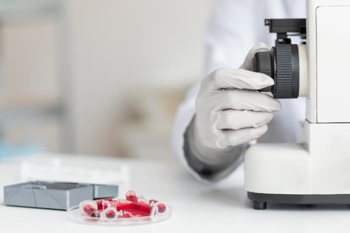 Ce-analize-se-fac-pentru-anemie-probe-de-sange-in-eppendorf-uri-placa-Petri-microscop-cutie-de-metal-deschisa-medic-mana-manusa-fundal-alb. Ce-analize-se-fac-pentru-anemie-probe-de-sange-in-eppendorf-uri-placa-Petri-microscop-cutie-de-metal-deschisa-medic-mana-manusa-fundal-alb.
